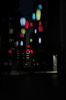 Colorful lanterns hanging in a narrow Kyoto alley during a local festival at night.