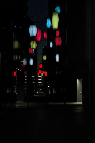 Colorful lanterns hanging in a narrow Kyoto alley during a local festival at night.