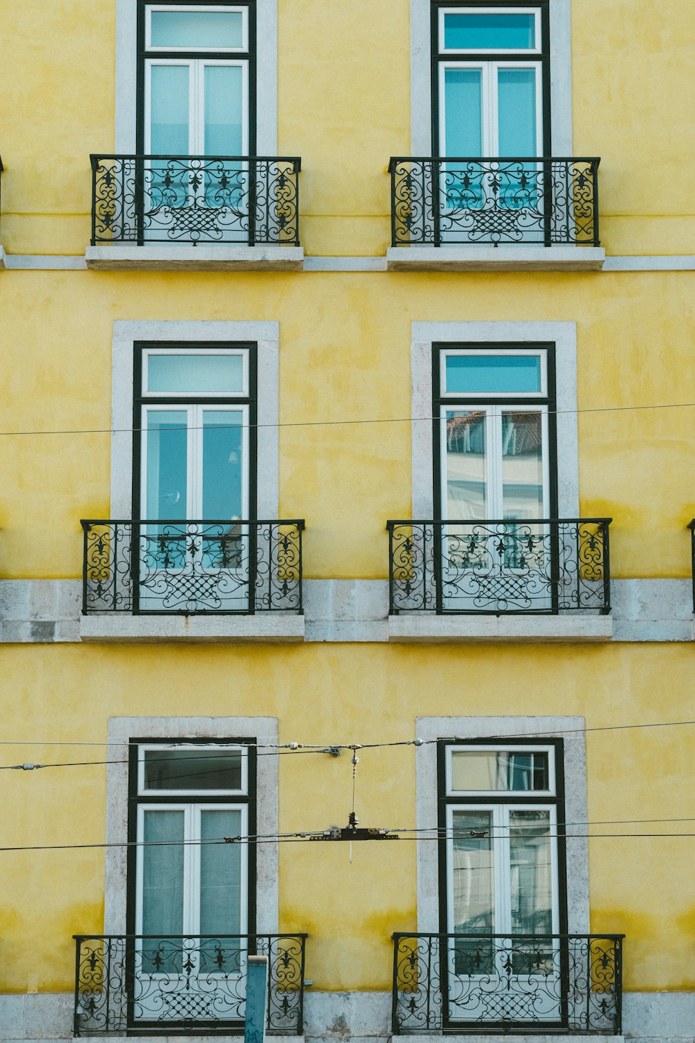 a tall yellow building with windows and balconies