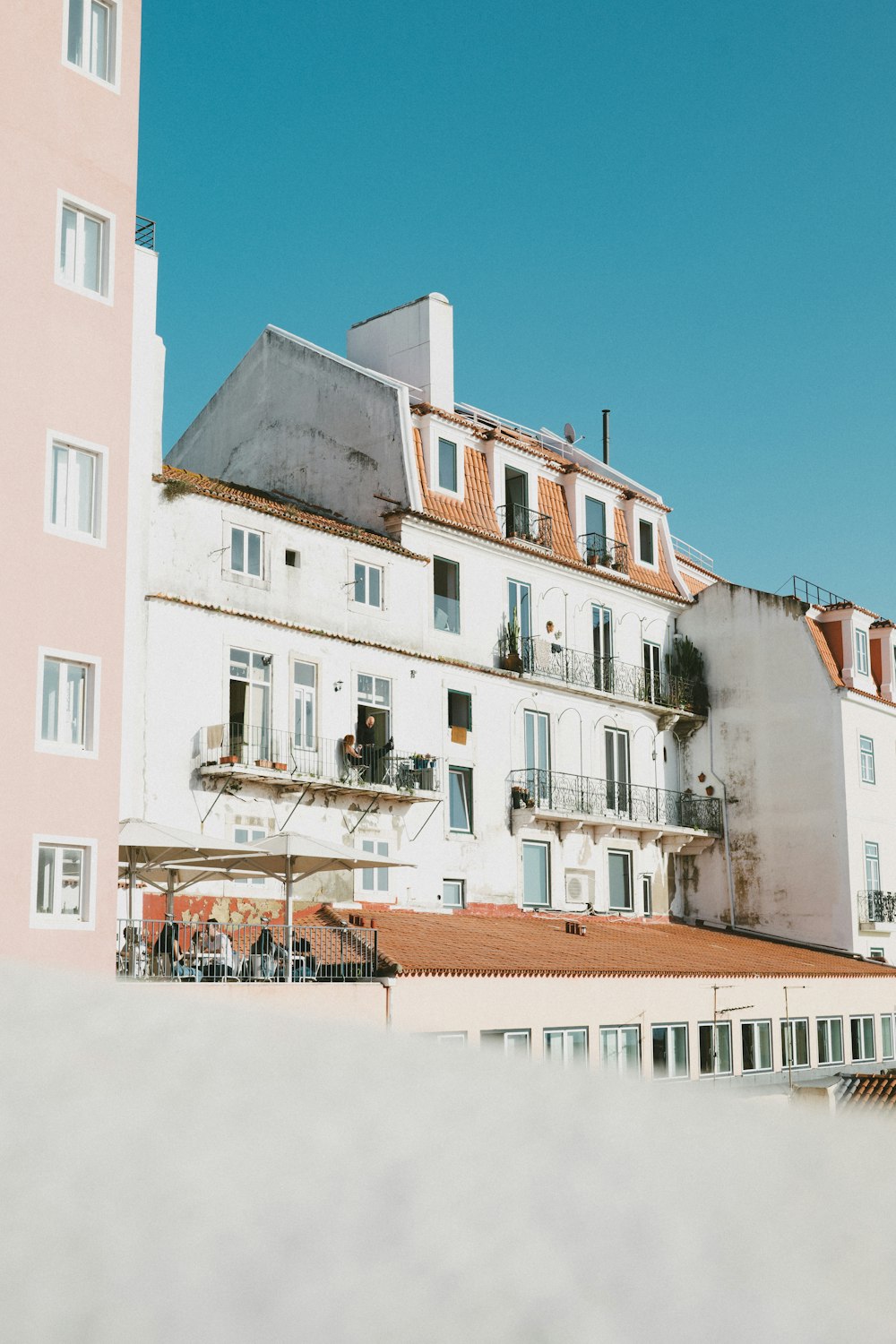 a tall white building sitting next to a tall pink building