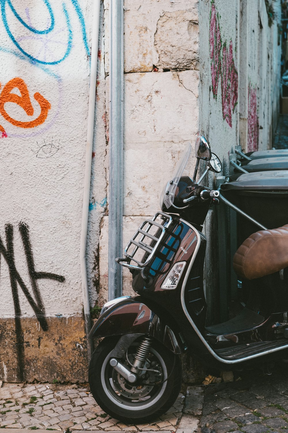 a scooter parked next to a wall with graffiti on it