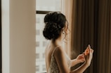 a woman standing in front of a window spraying perfume