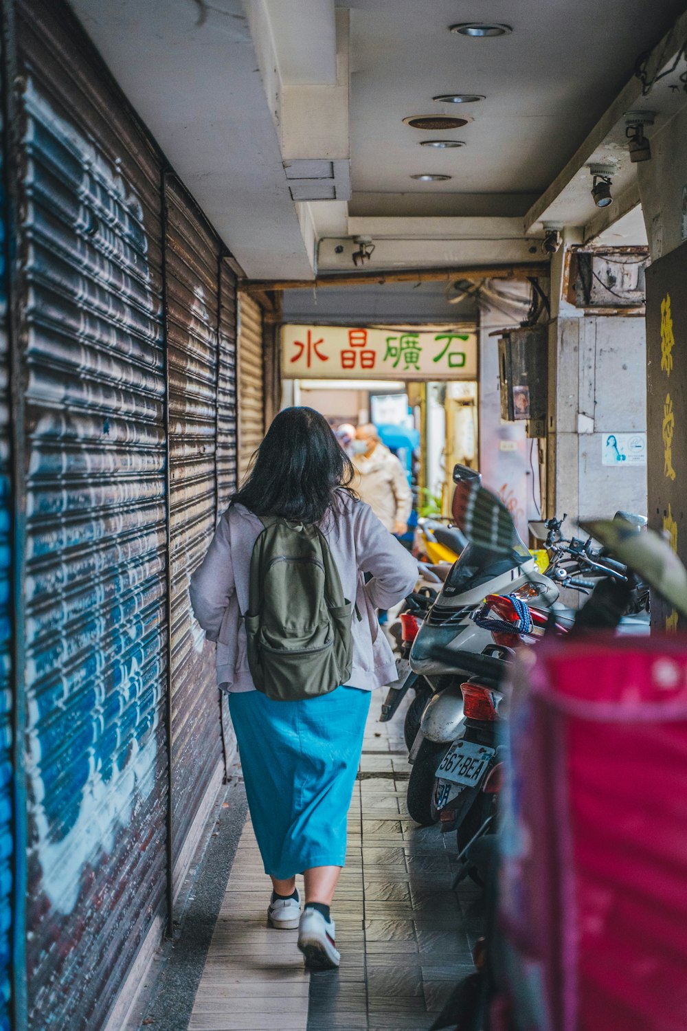 a woman walking down a street next to parked motorcycles