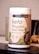A container labeled 'Youthful Living Keto Vegan Protein Shake' is prominently displayed. The container highlights its plant-based ingredients and is flavor 'Cafe Mocca'. It's positioned on a reflective surface with part of a banana visible in the background.
