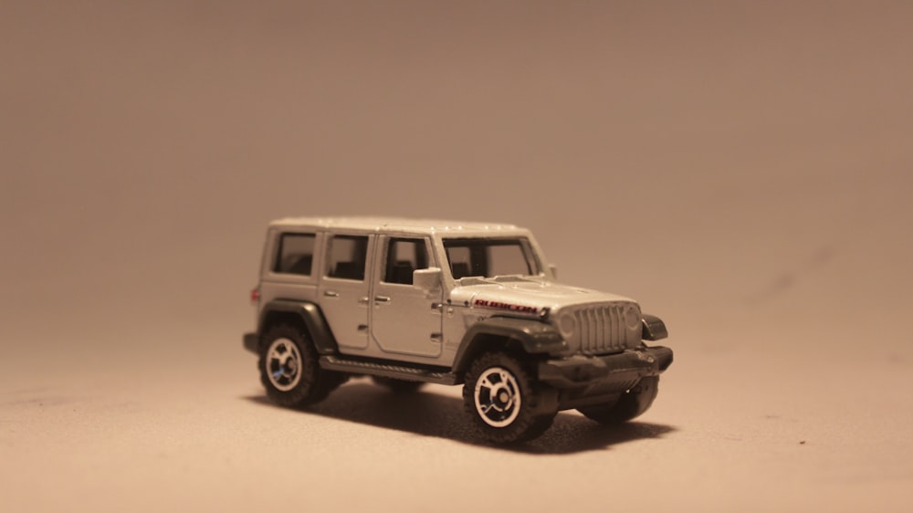 a toy jeep is shown on a plain surface