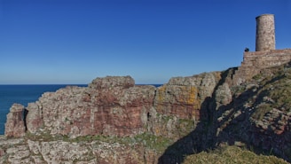 a tall tower sitting on the side of a cliff next to the ocean
