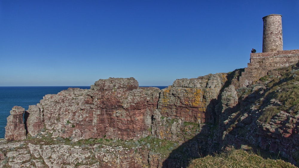 a tall tower sitting on the side of a cliff next to the ocean