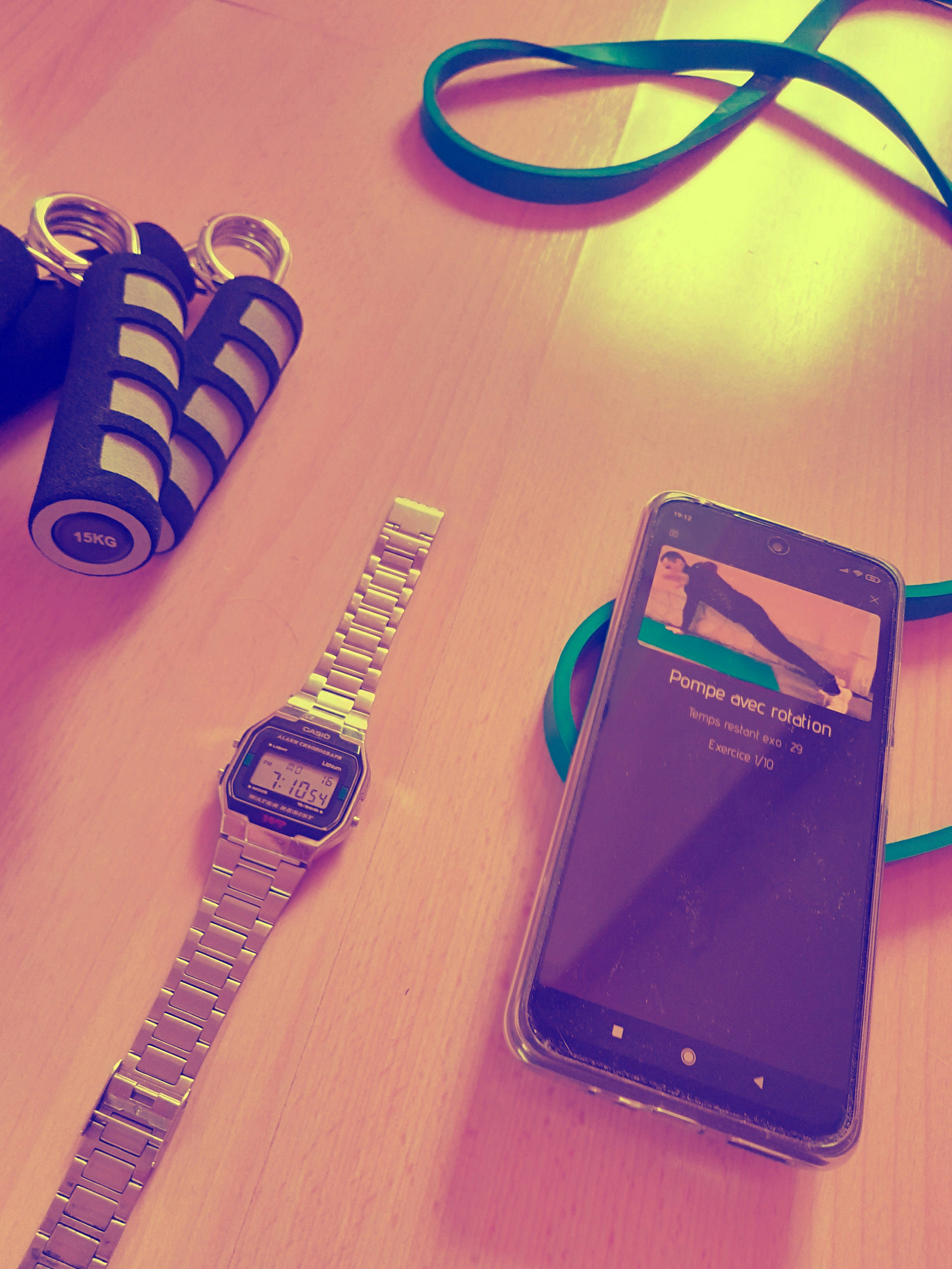 Person checking a fitness app on a phone, workout gear on a wooden floor