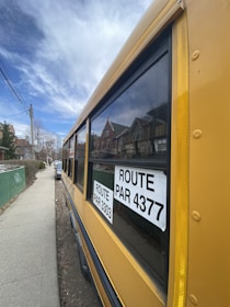 A bright yellow school bus picking up children in a residential area.