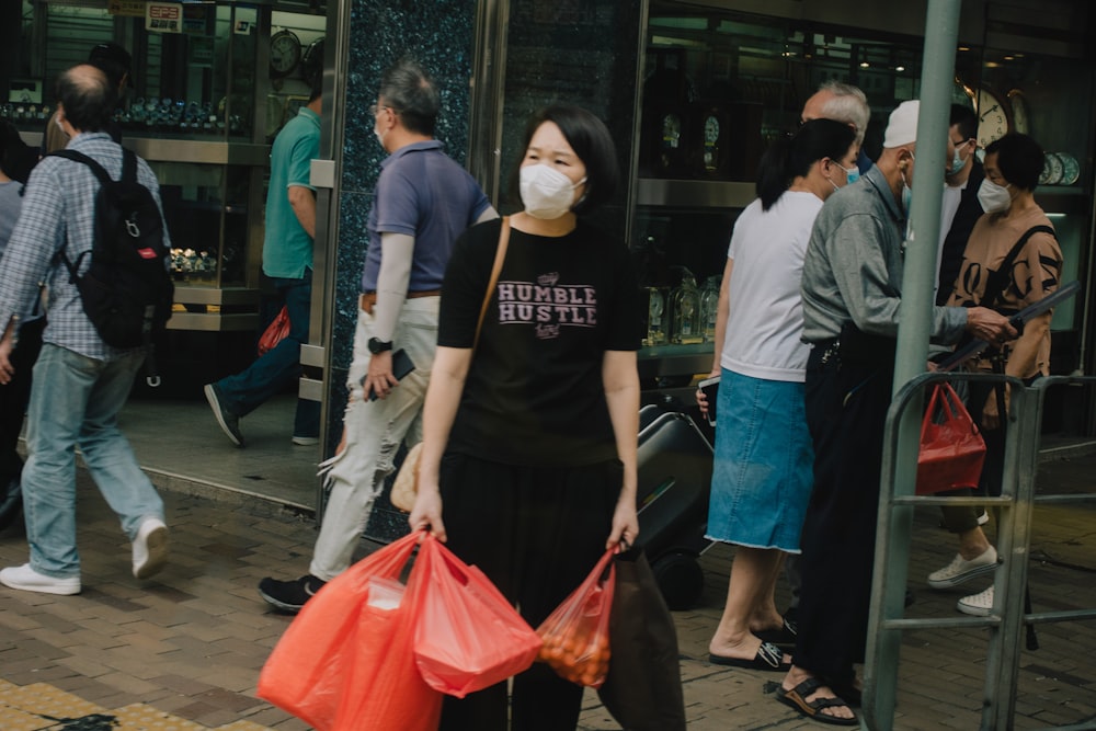 a woman wearing a face mask carrying shopping bags