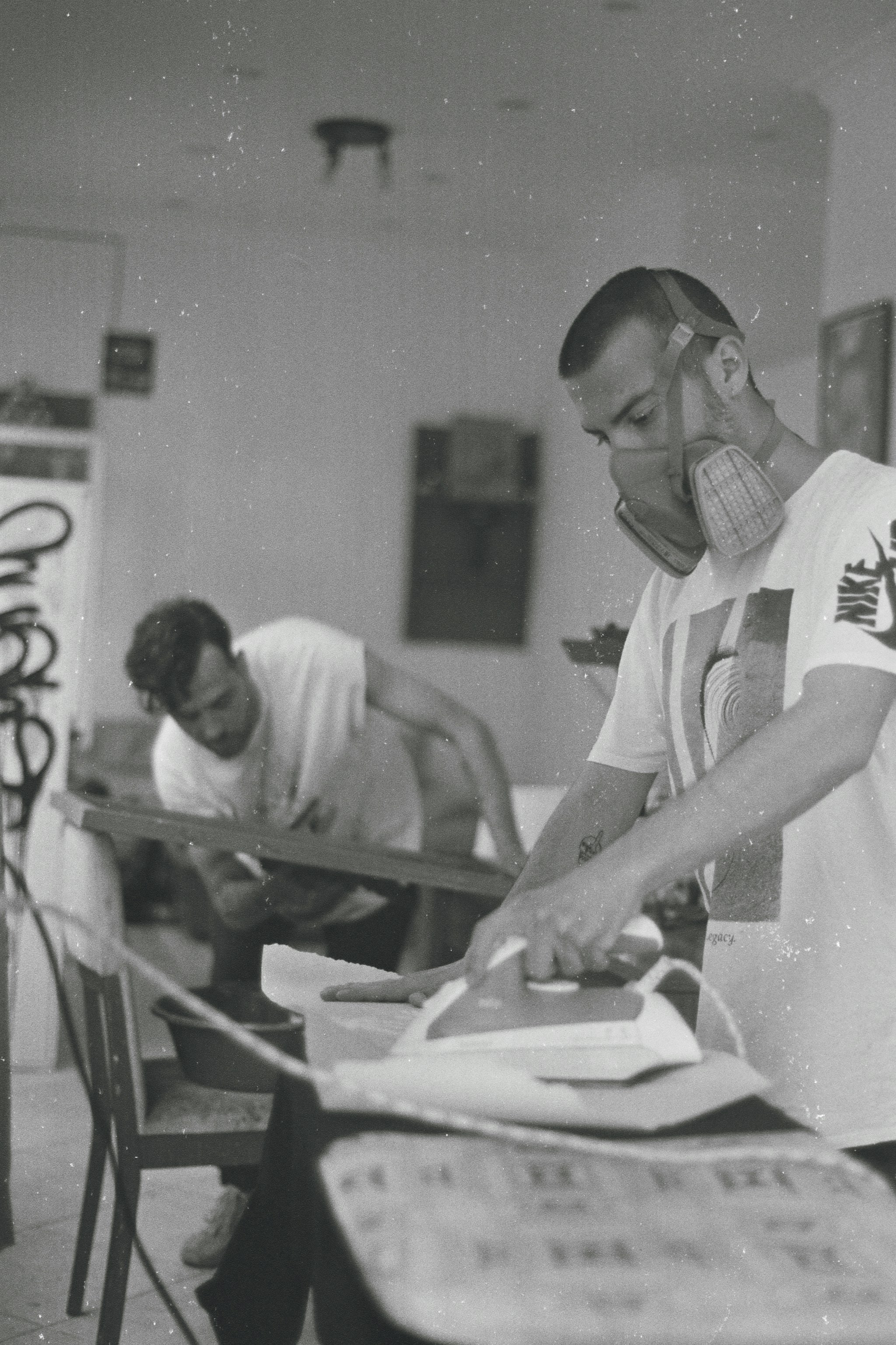 a black and white photo of a man ironing