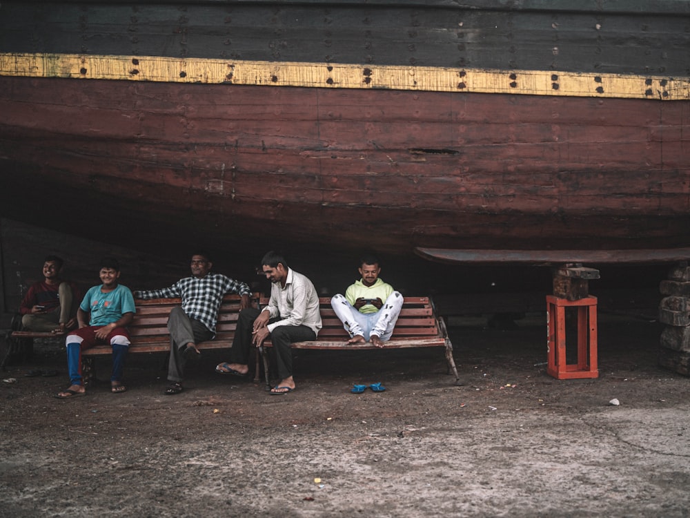 a group of people sitting on a bench next to a boat