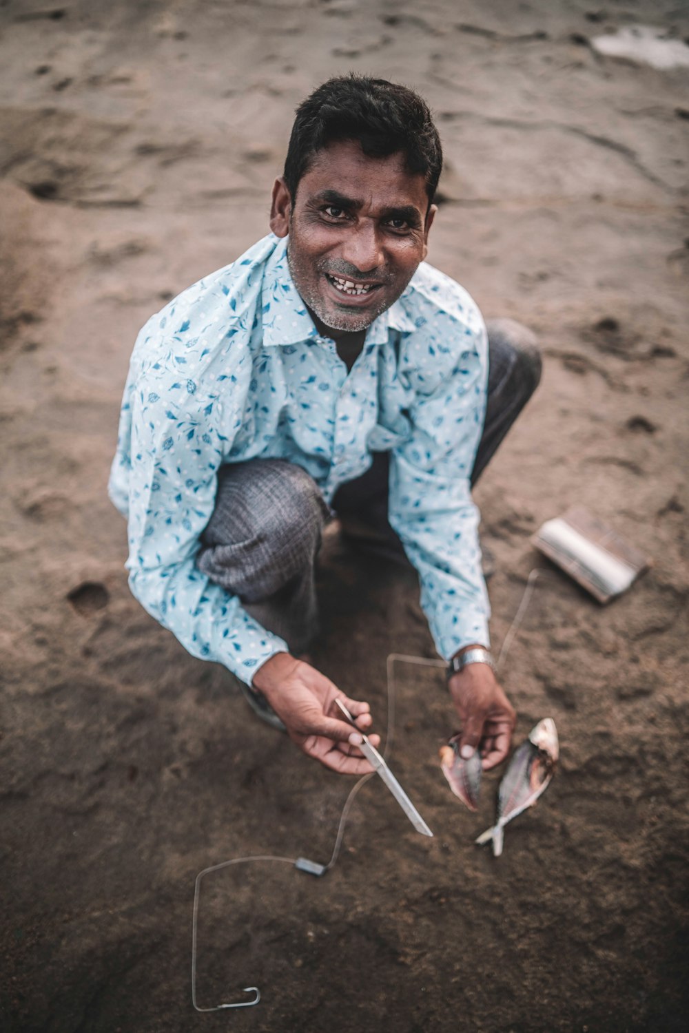 a man sitting on the ground holding a pair of scissors