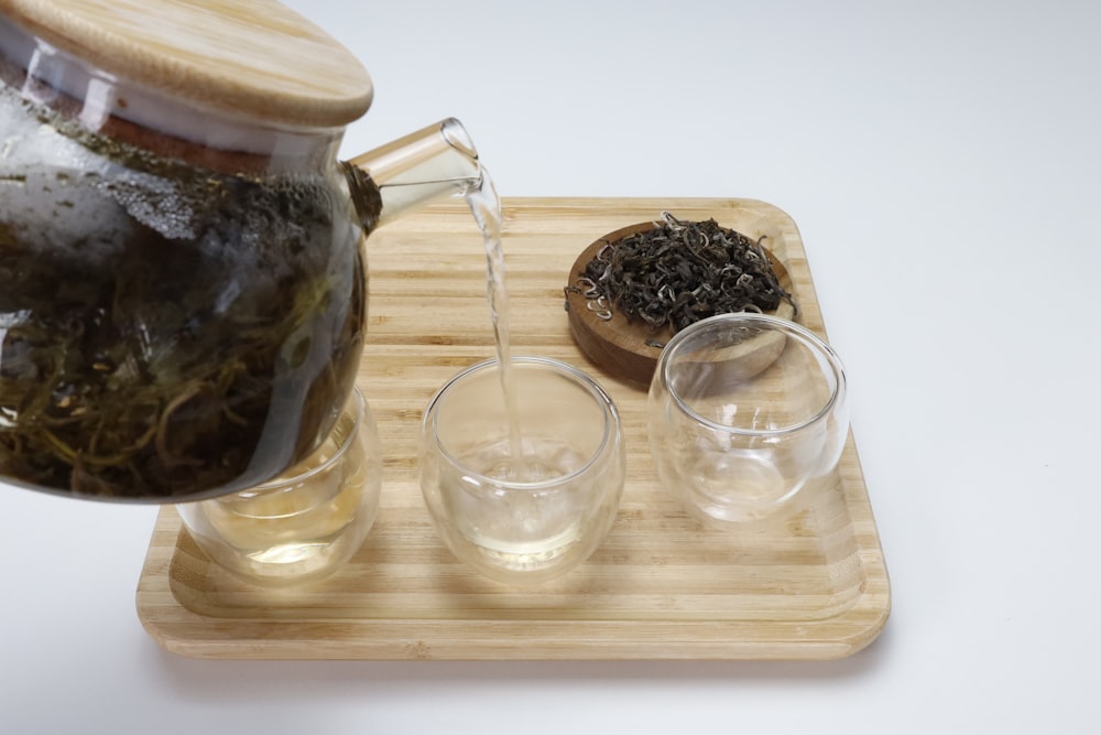 a tea pot pouring tea into two glasses