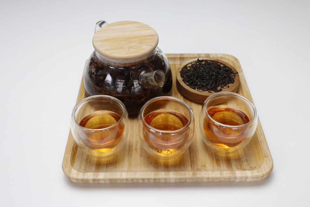 a tray with four glasses of tea and a tea pot