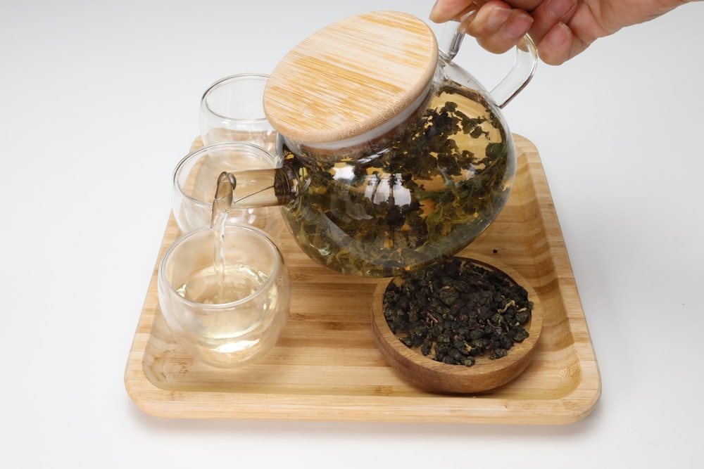 a person pours tea into a glass pitcher