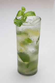 Tall glass showcasing a refreshing mojito with crushed ice, mint leaves, and a lime slice