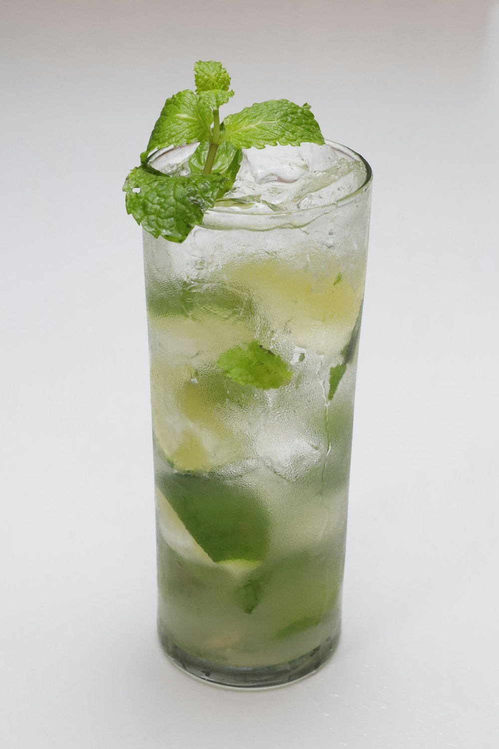 a tall glass filled with ice and mint