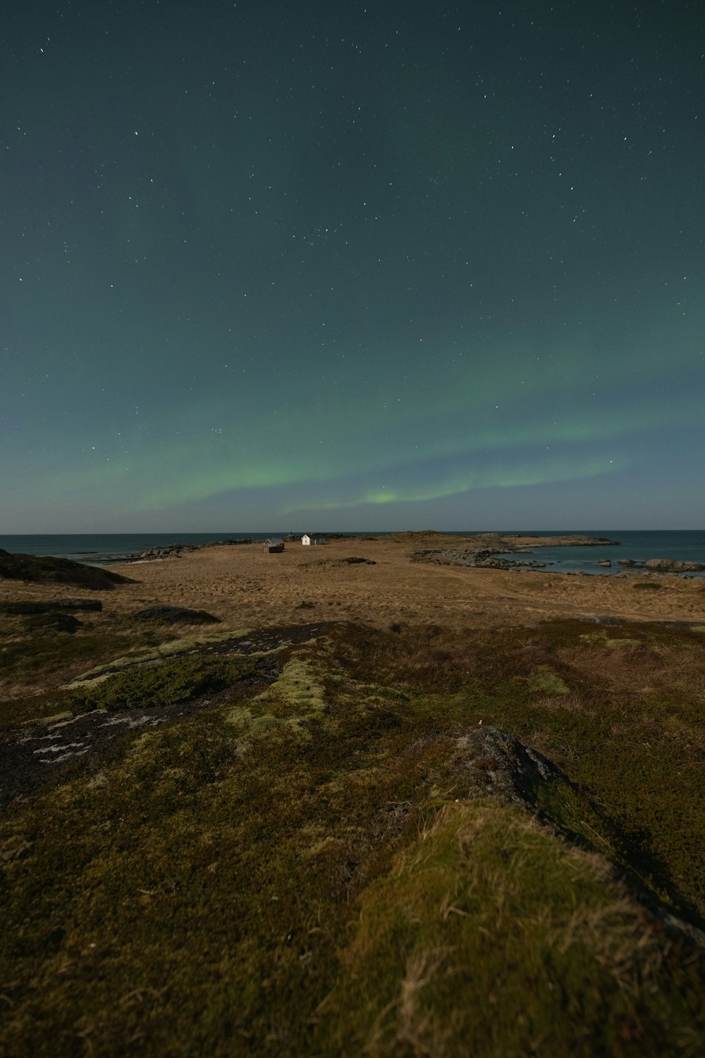 a grassy field with a light house in the distance