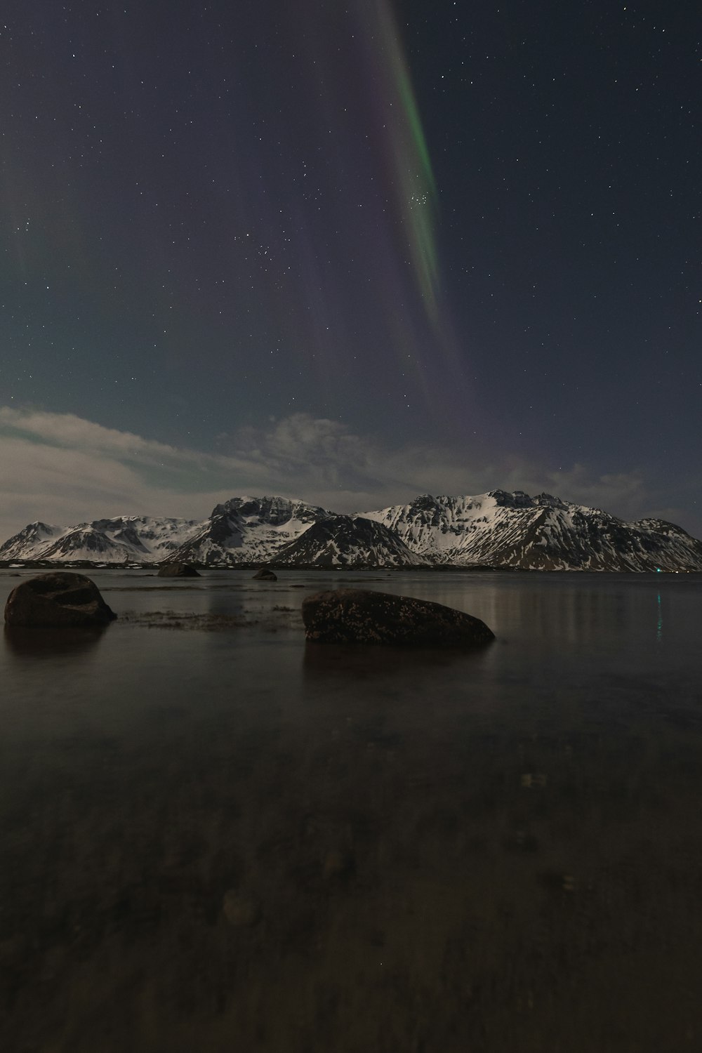a night time view of a mountain range and a body of water