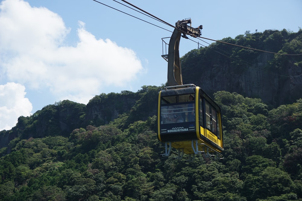 a yellow cable car going up a mountain side