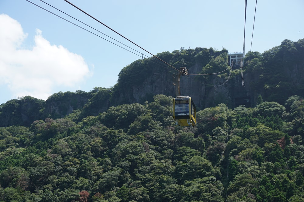 a yellow cable car going up a mountain side