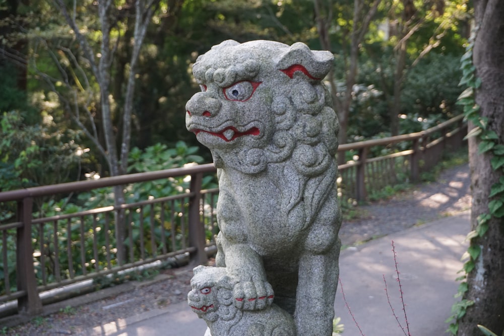 a stone lion statue in a park setting