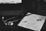 a notebook with a stethoscope on top of it next to a laptop