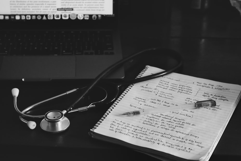 a notebook with a stethoscope on top of it next to a laptop