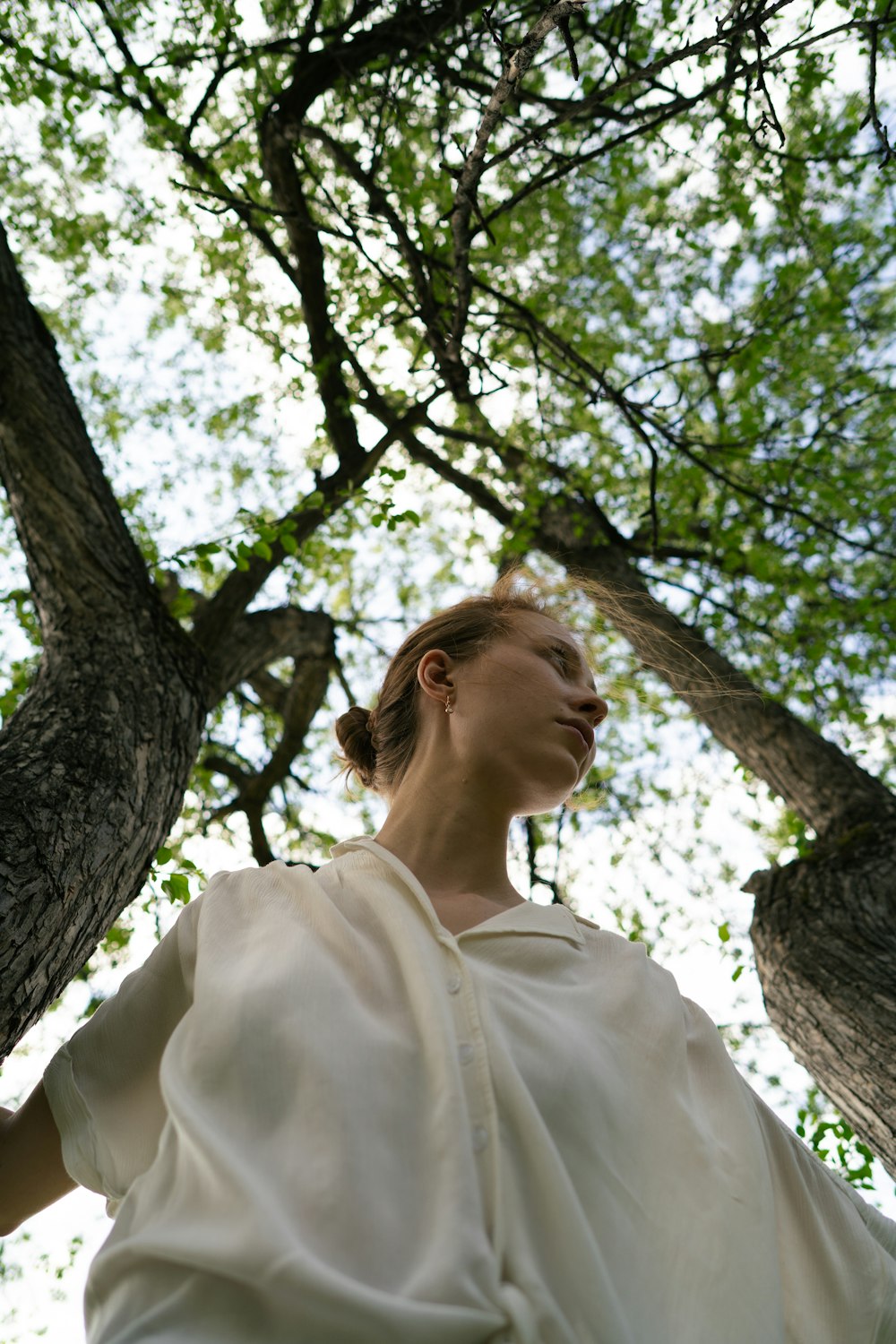 a woman in a white dress standing in front of a tree