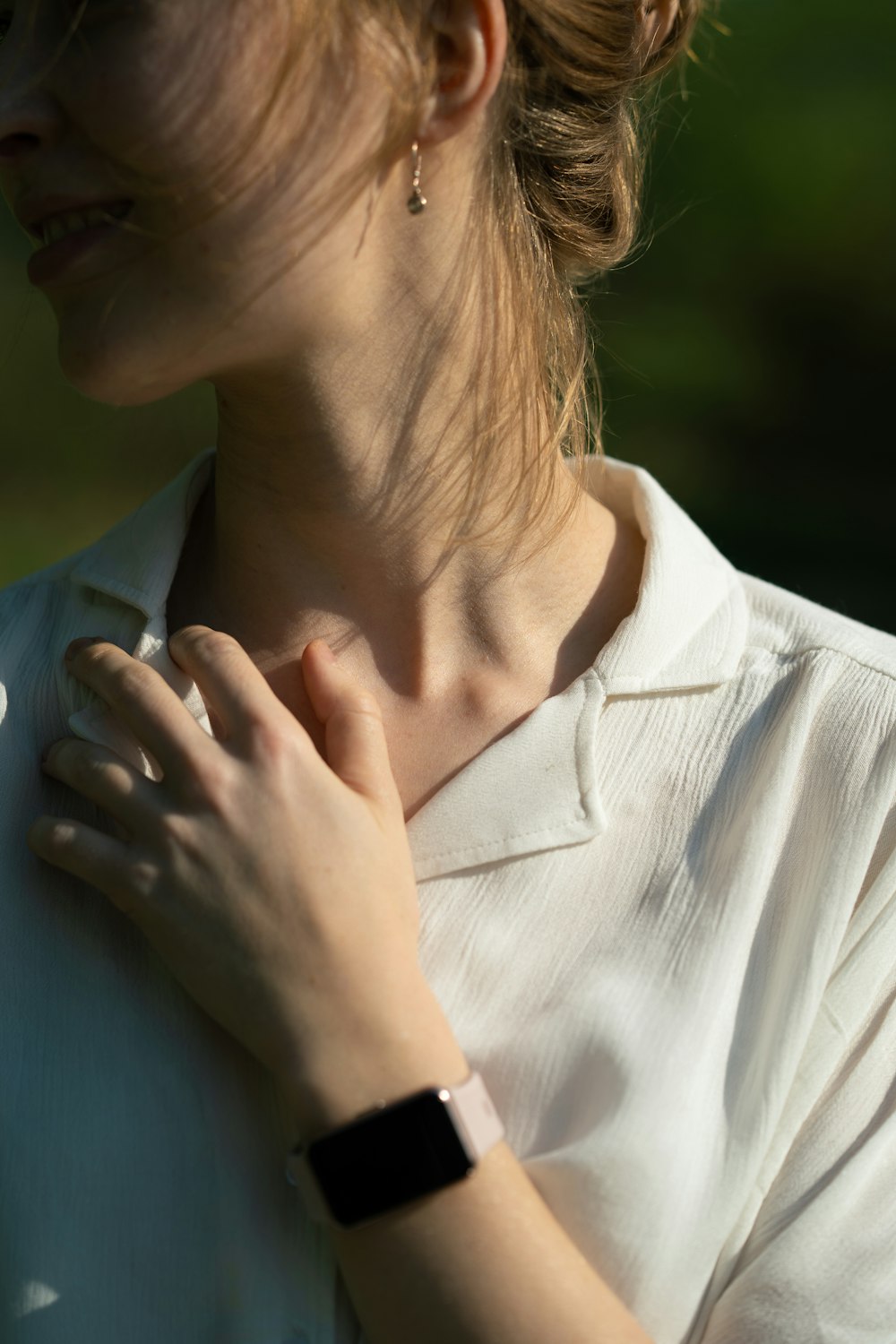 a woman wearing a white shirt and a black watch