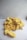 A pile of dried jackfruit pieces is placed on a plain white surface. The jackfruit pieces are bright yellow and have a wrinkled texture.