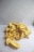 A pile of dried jackfruit pieces is placed on a plain white surface. The jackfruit pieces are bright yellow and have a wrinkled texture.