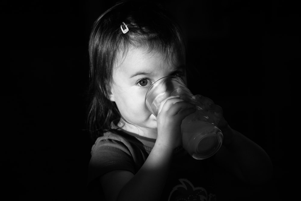 a little girl drinking from a bottle in the dark