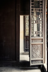 A craftsman carefully fitting a large custom wooden door into a modern interior doorway.