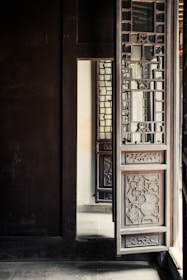 Artisan handcrafting a wooden door with detailed carvings in a sunlit workshop.