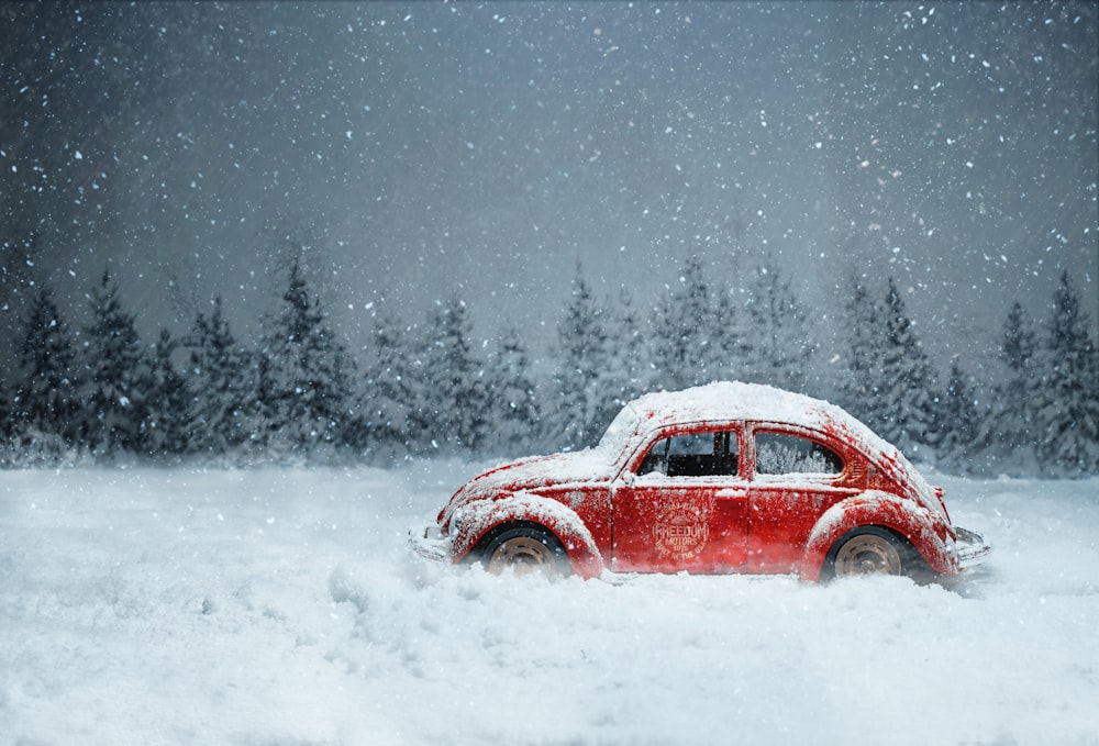 a red car driving through a snow covered forest