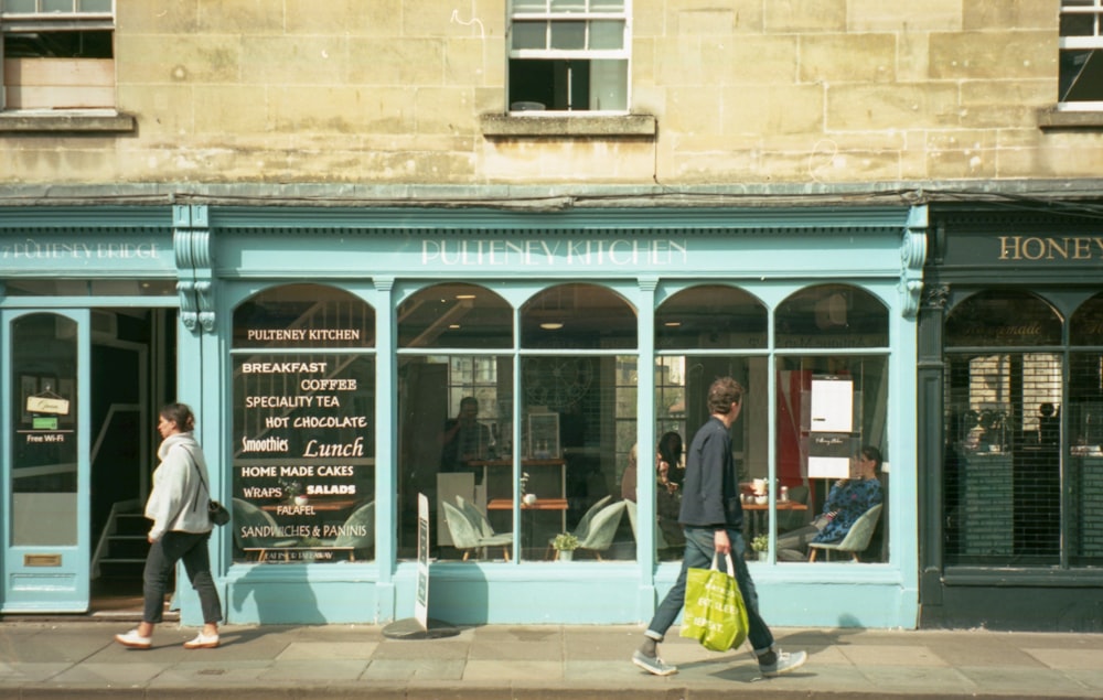 a couple of people walking past a store front