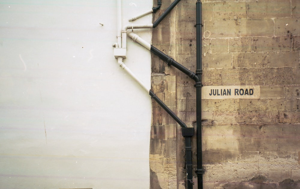 a street sign on a brick wall next to a pipe