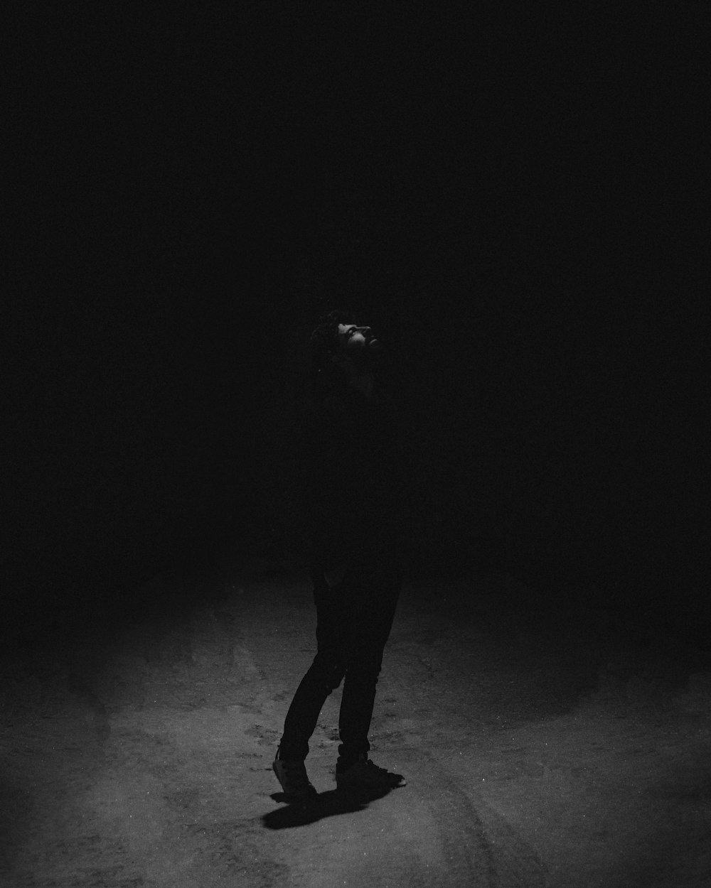 a man standing in the dark with his head down