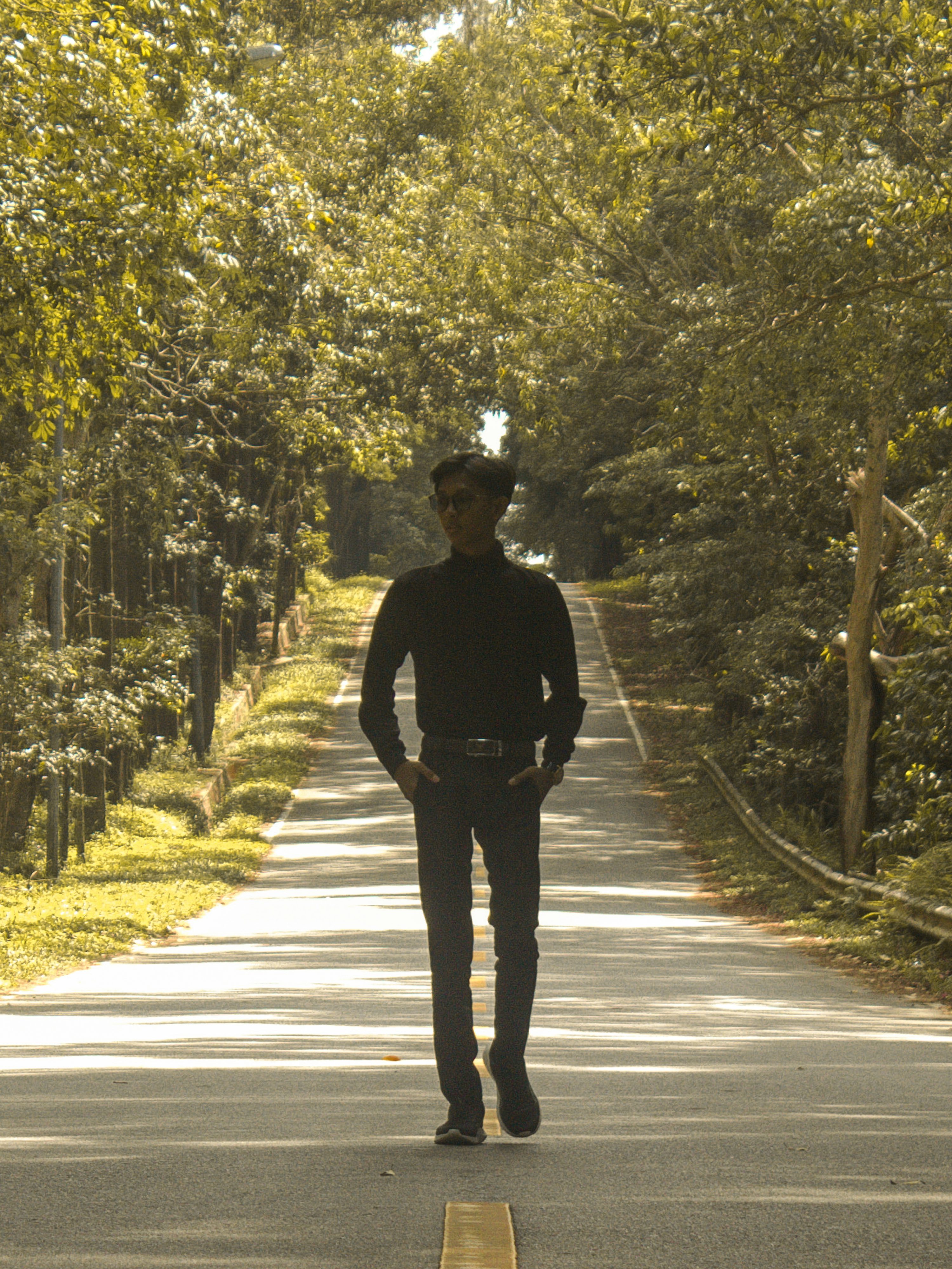 a man walking down a road with a skateboard