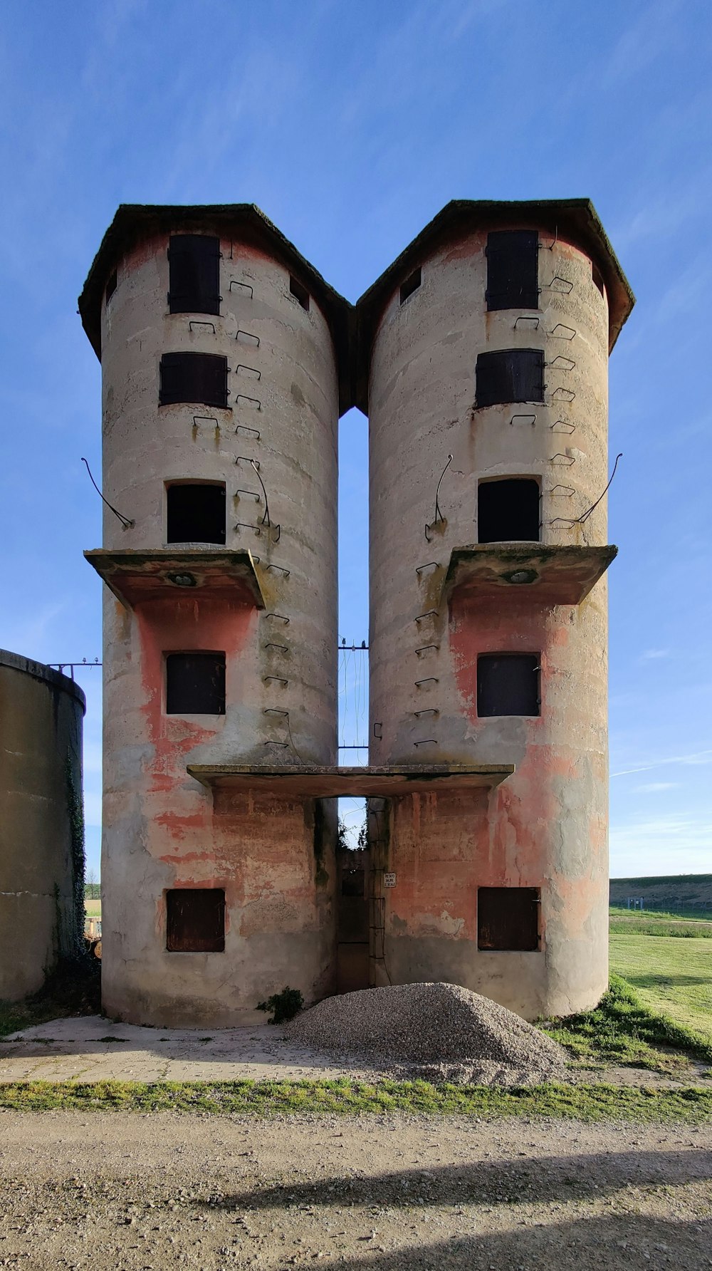 a couple of tall buildings sitting on top of a dirt field