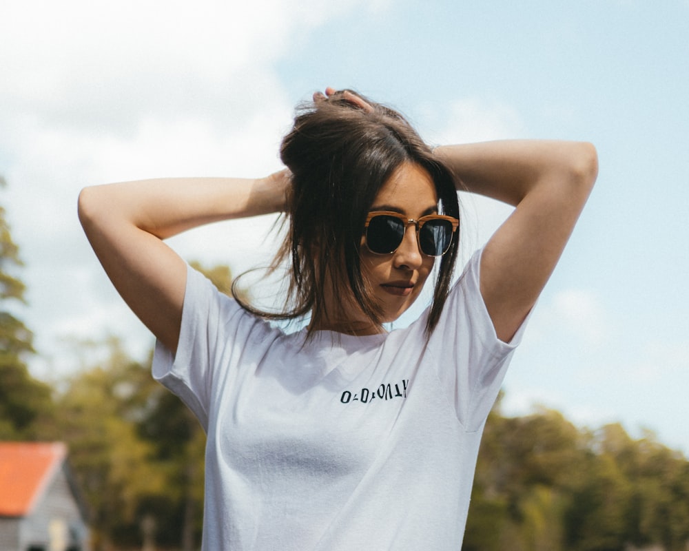 a woman wearing sunglasses and a white shirt