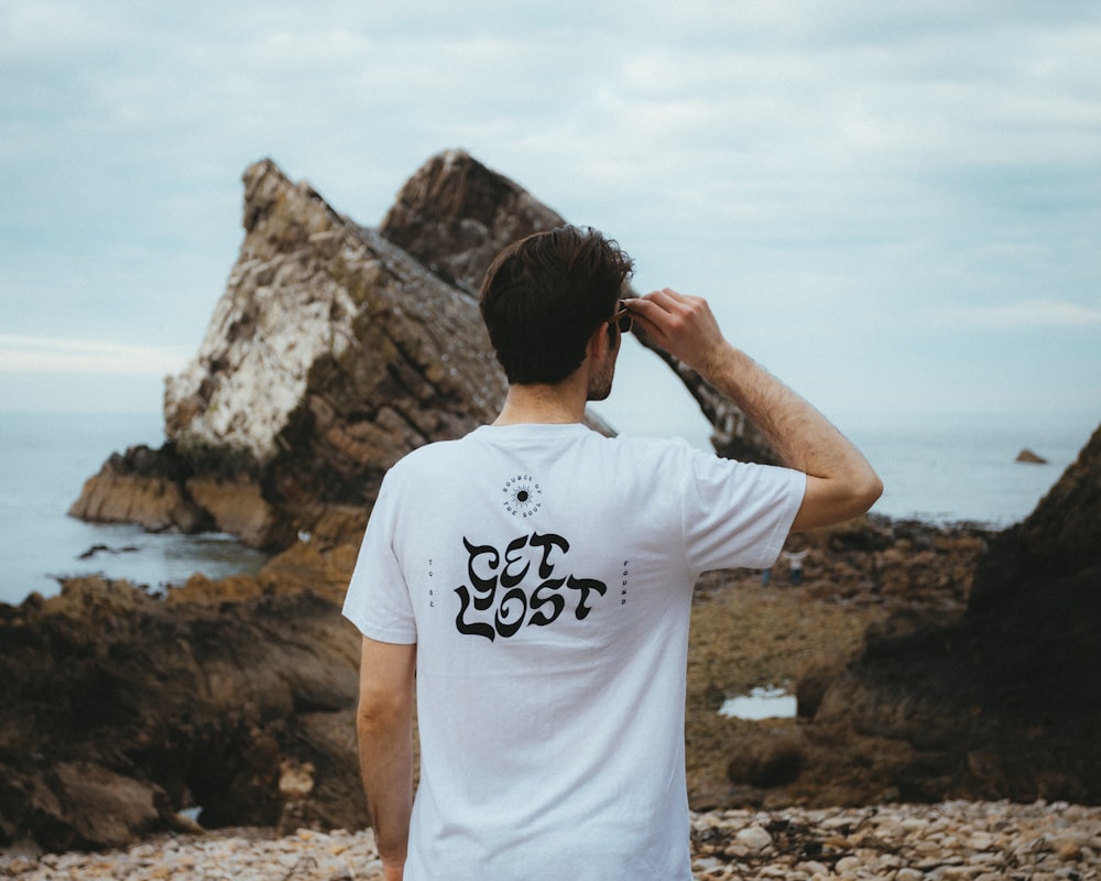 a man standing on top of a rocky beach next to the ocean