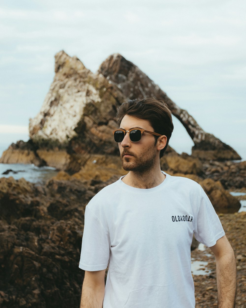 a man standing on a rocky beach next to the ocean