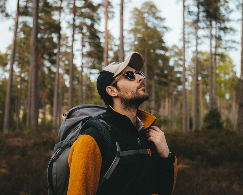 a man wearing a hat and sunglasses in the woods