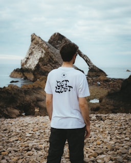 a man standing on a rocky beach next to the ocean