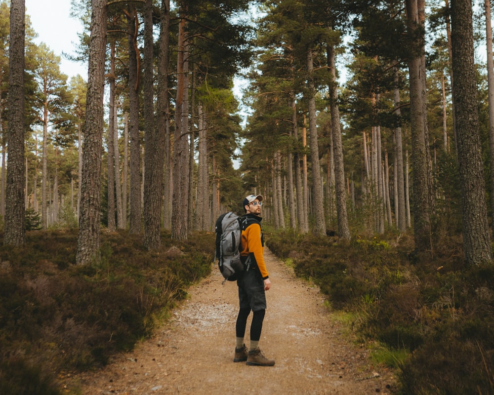 a man with a backpack is walking down a path in the woods