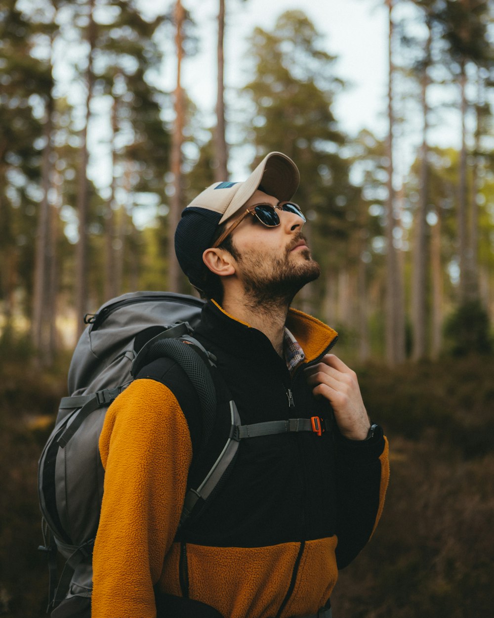 a man with a hat and a backpack in the woods