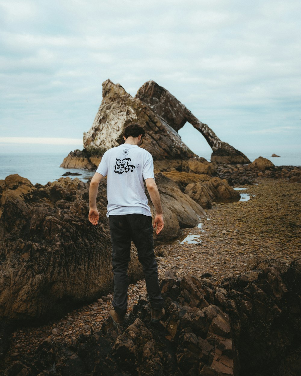 a man standing on a rocky beach next to the ocean